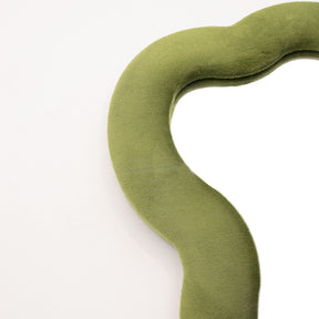 Close-up of moss green velvet texture on padded frame, showing plush finish and irregular cloud-like squiggly edge detail