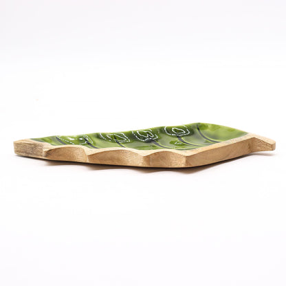 Large leaf-shaped mango wood bowl with rich green enamel inside, filled with pine cones and candles on autumn table setting