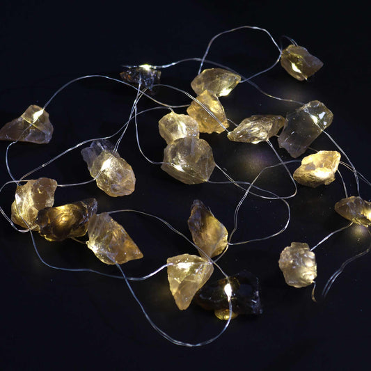 Close-up of individual citrine-inspired glowing bulbs on string lights, showing sunny yellow-orange hue and delicate wire