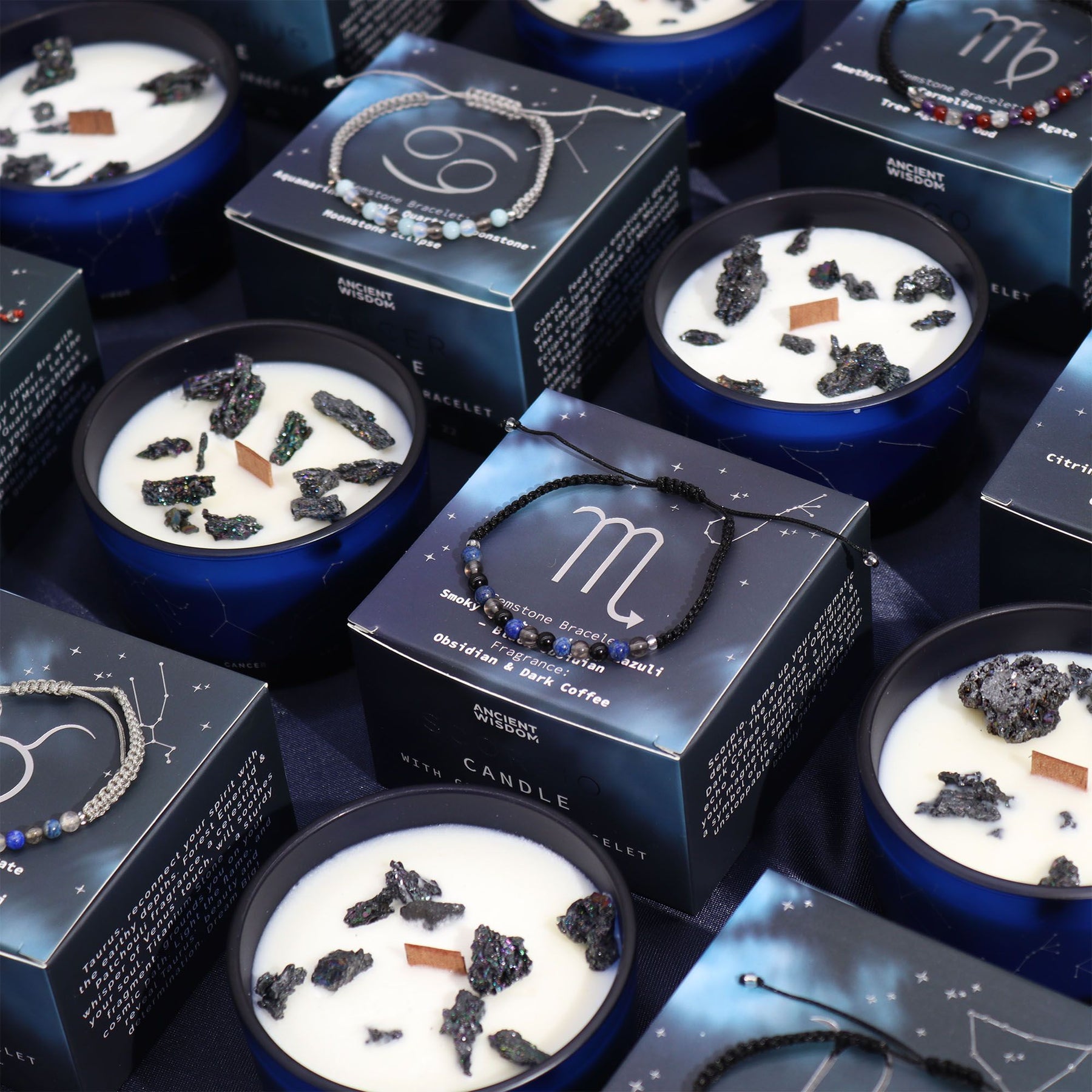 Candles with decorative elements and branded boxes on a dark surface