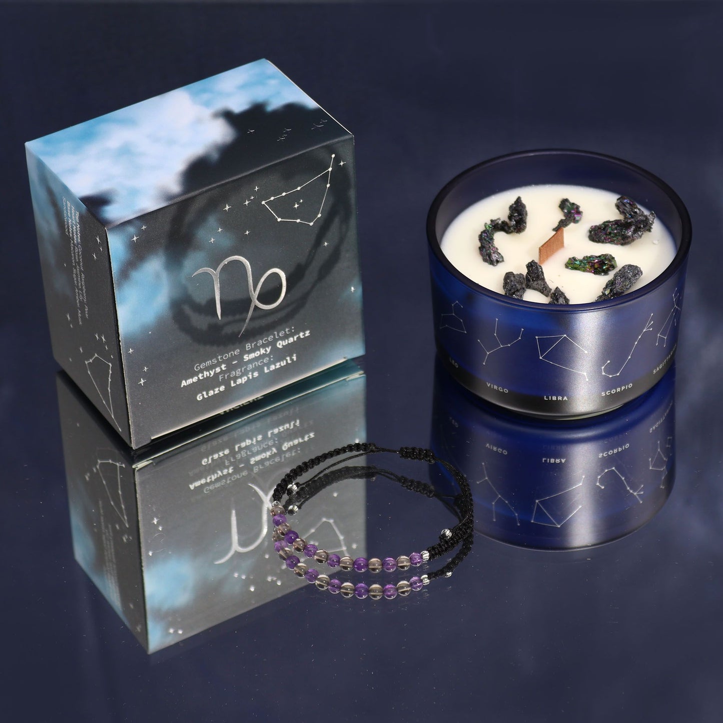 Navy & gold Capricorn zodiac candle burning beside matching amethyst & smoky quartz bracelet, styled with Capricorn constellation card and mountain crystals