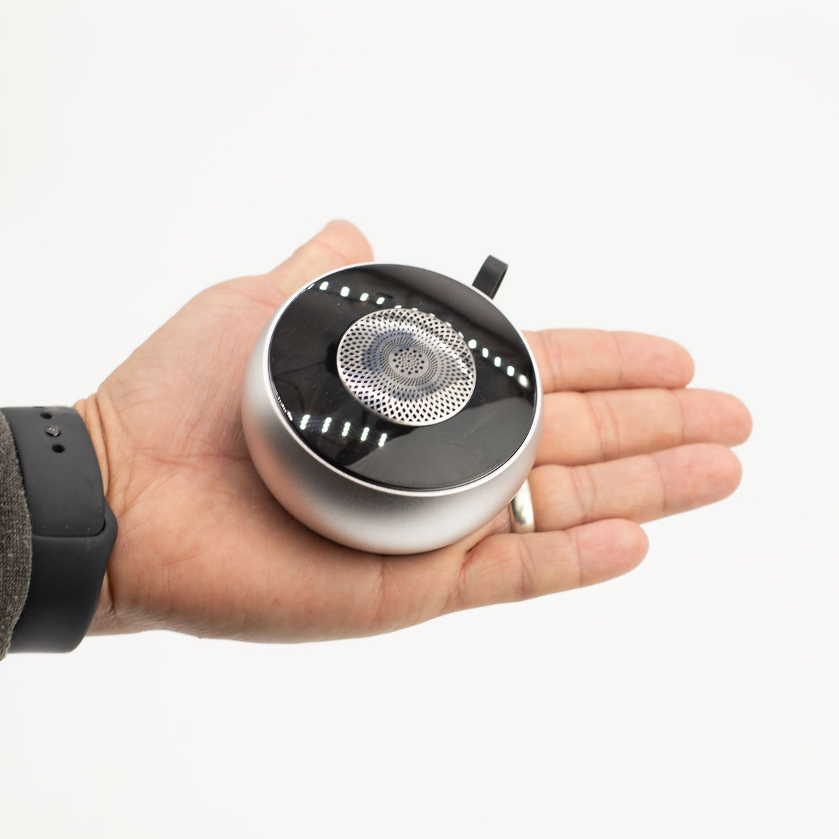 Mandala speaker in hand demonstrating pocket-sized portability and integrated carry loop