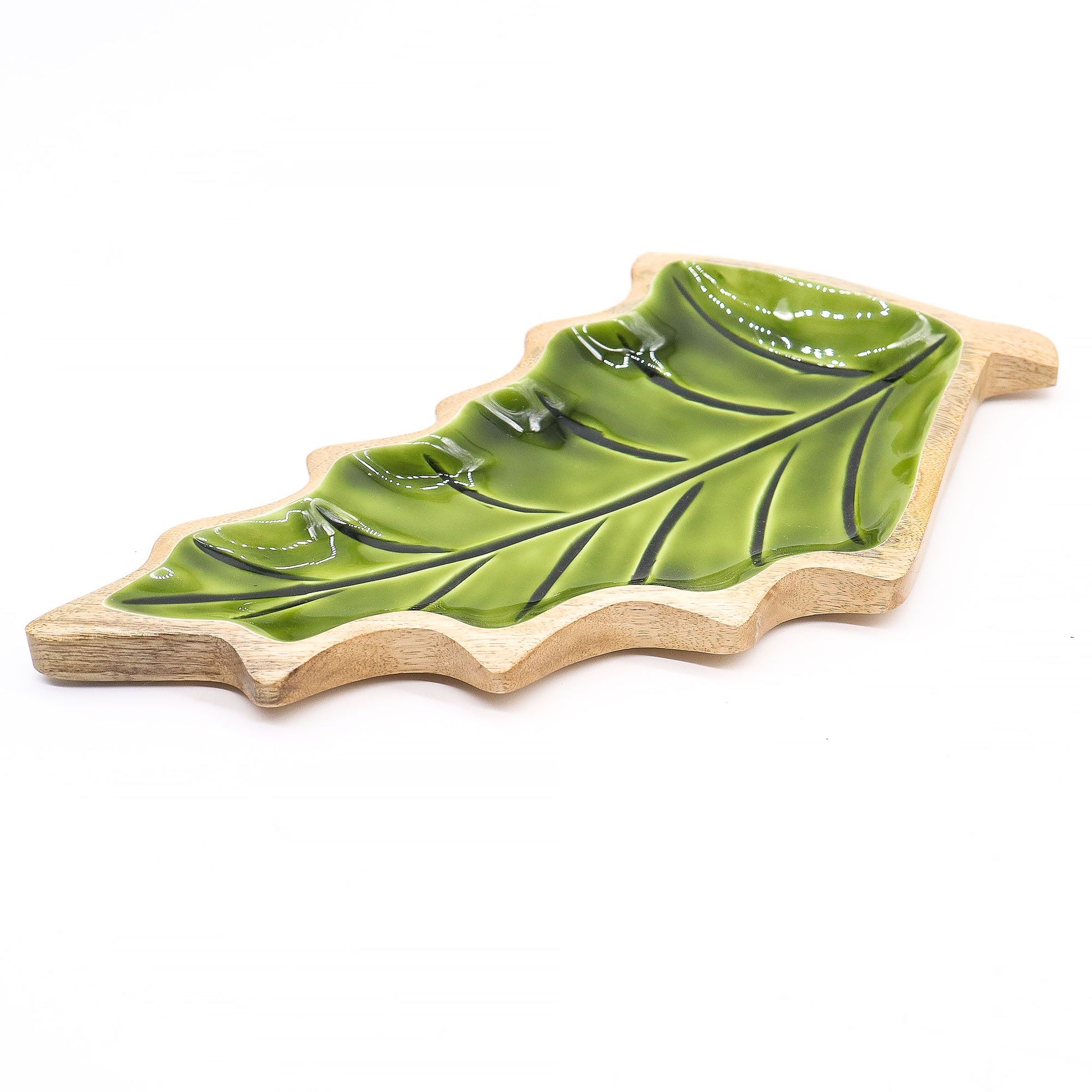 Large leaf-shaped mango wood bowl with rich green enamel inside, filled with pine cones and candles on autumn table setting
