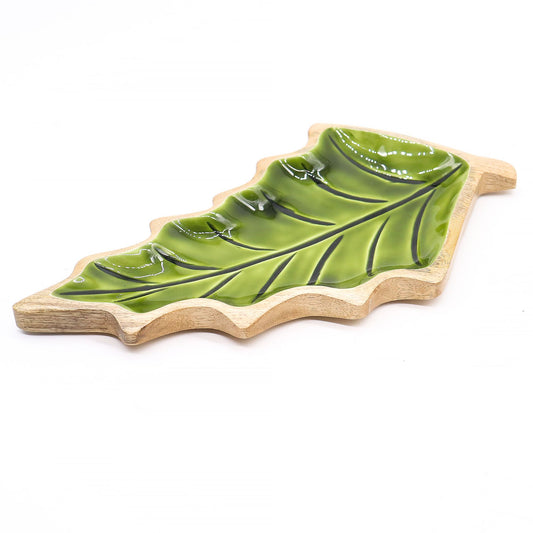 Large leaf-shaped mango wood bowl with rich green enamel inside, filled with pine cones and candles on autumn table setting