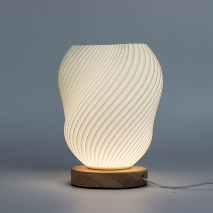 Close-up of lamp’s textured honeycomb pattern and soft diffused light, showing elegant twisted shell-like silhouette and wooden base detail