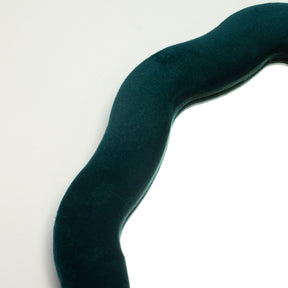 Close-up of royal teal velvet texture on padded frame, showing plush finish and irregular pebble-like squiggly edge detail