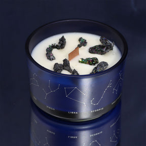 Candle in a blue container with star constellations on a dark background
