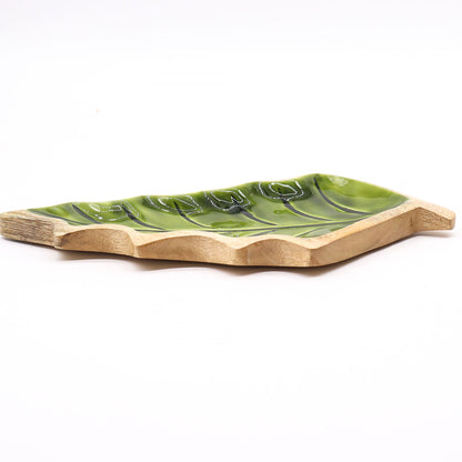 Large leaf-shaped mango wood bowl with rich green enamel inside, filled with pine cones and candles on autumn table setting