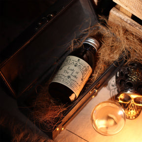 140ml amber glass bottle of Lady of the Lake ritual water with sword-in-lake label, surrounded by fresh basil, lemongrass, misty water and Excalibur sword