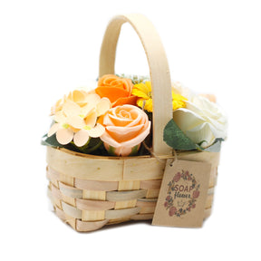 Medium orange soap flower bouquet with lifelike roses and blooms beautifully arranged in natural wicker basket, tied with ribbon, presented as luxury bath gift on soft white background