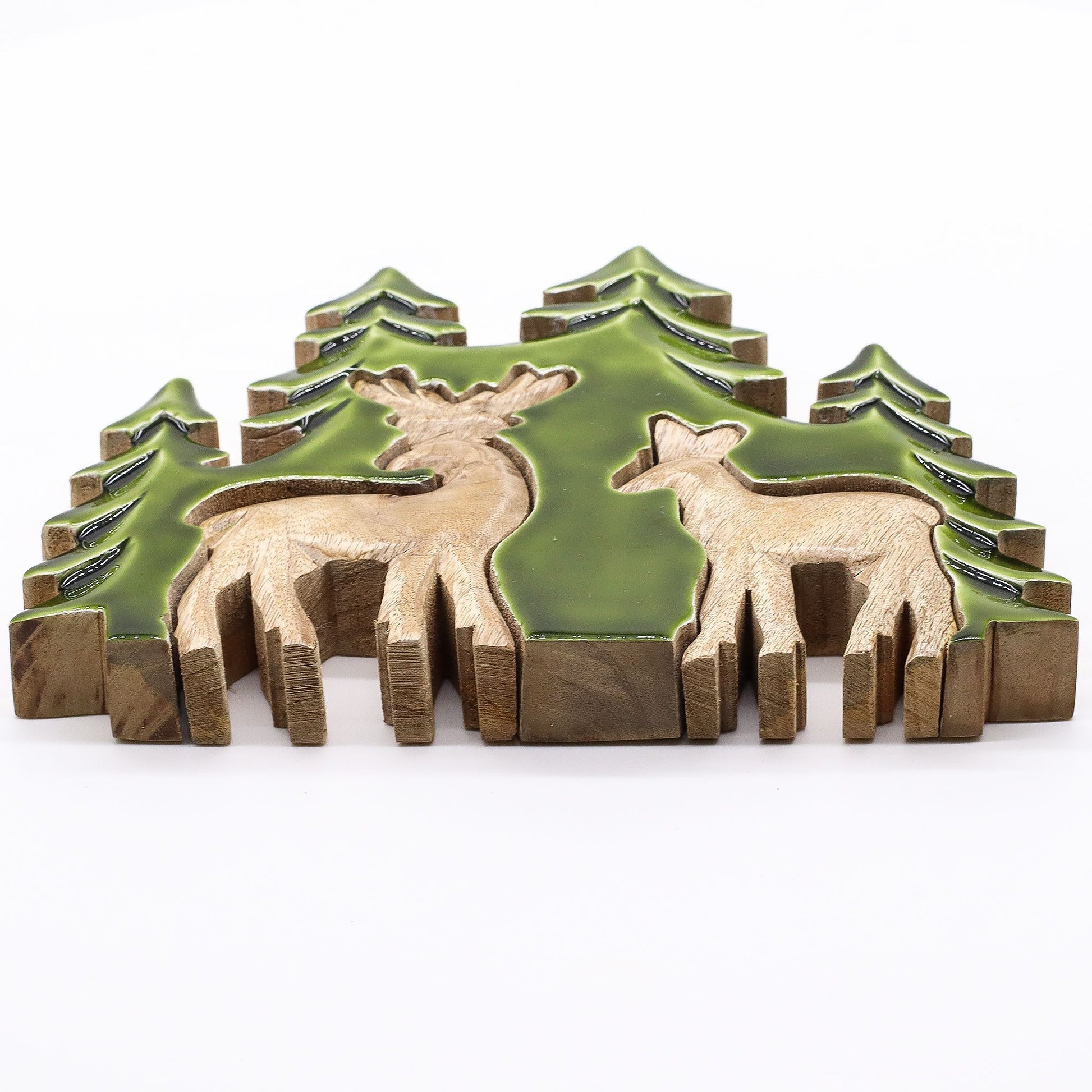 3D mango wood deer in forest decoration with two standing deer, green enamel trees and layered woodland scene on mantel with fairy lights and pine cones