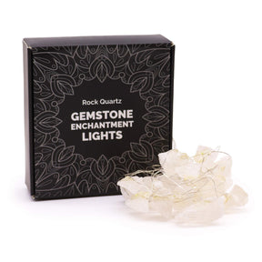 Clear quartz crystal fairy lights sparkling in glass bowl on meditation altar with sage, candles and moon phases in serene setting