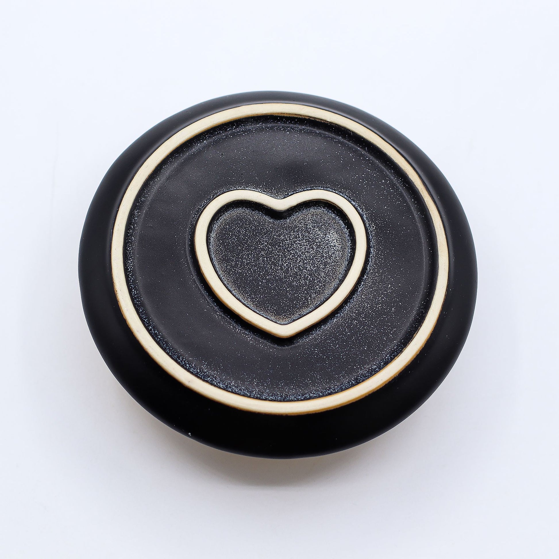 Black bottom of incense burner with a gold heart-shaped cutout