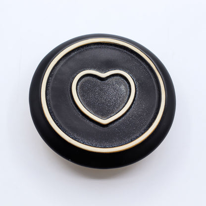 Black bottom of incense burner with a gold heart-shaped cutout