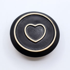 Black bottom of incense burner with a gold heart-shaped cutout