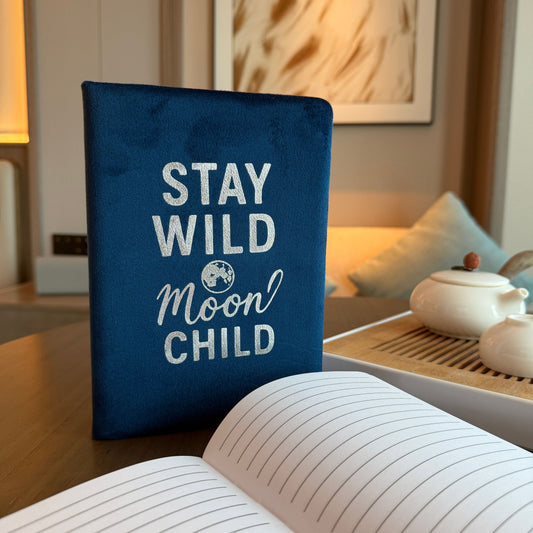 Deep blue velvet notebook with glowing silver “Stay Wild Moon Child” script