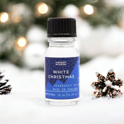 10ml White Christmas fragrance oil bottle surrounded by frosted pine, snowflakes and glittering snow on dark winter background
