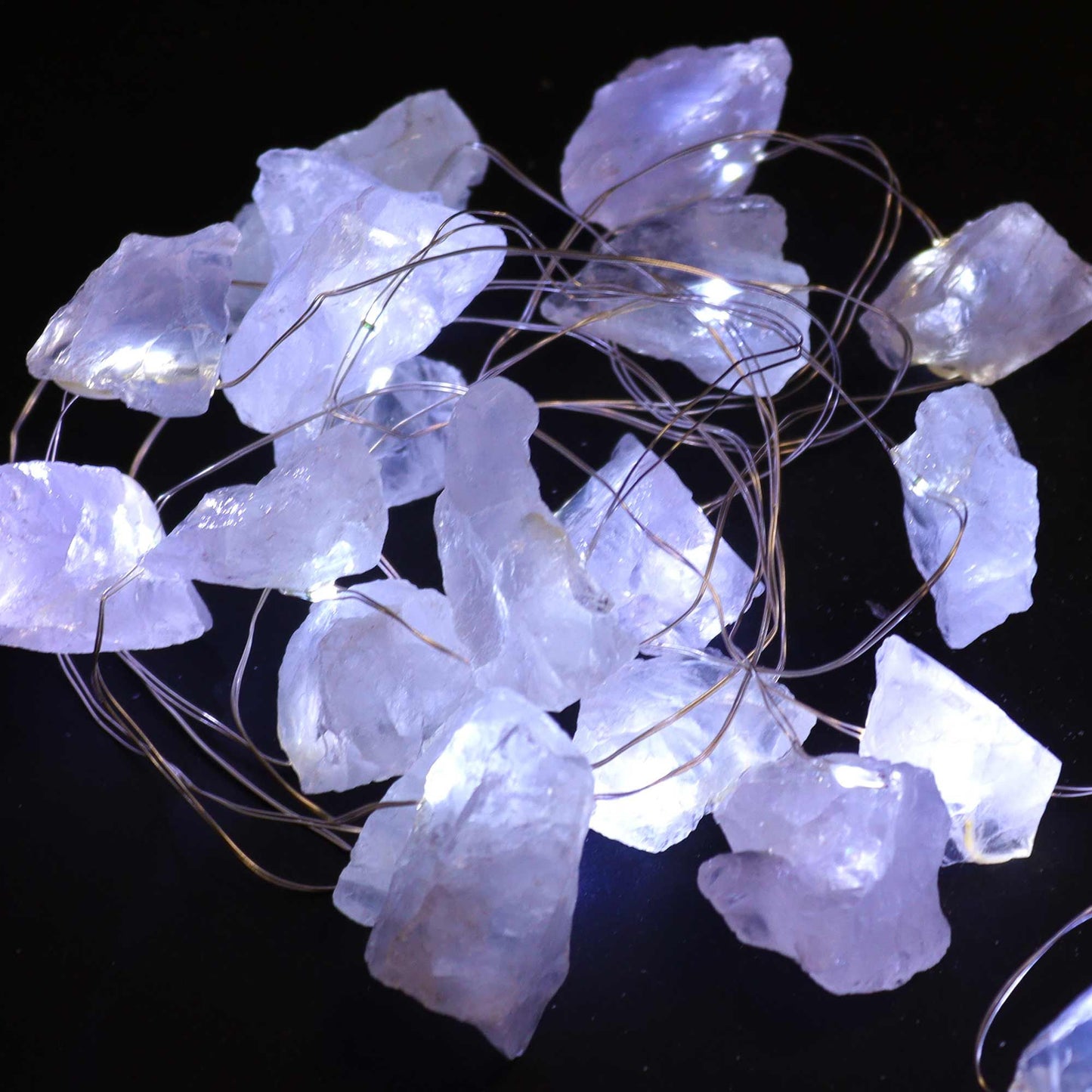 Clear quartz crystal fairy lights sparkling in glass bowl on meditation altar with sage, candles and moon phases in serene setting