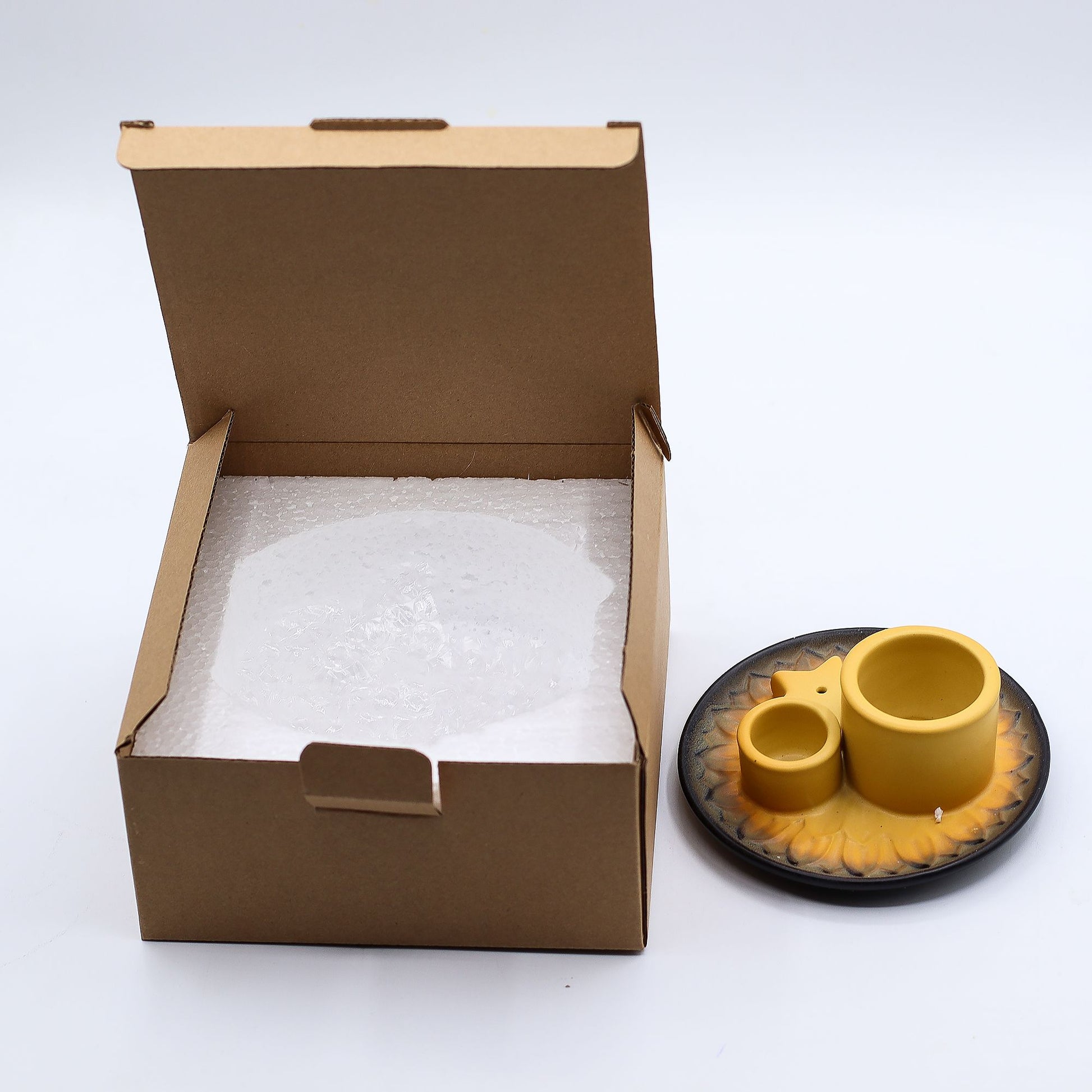 Open cardboard box with bubble wrap next to a set of yellow ceramic incense holder