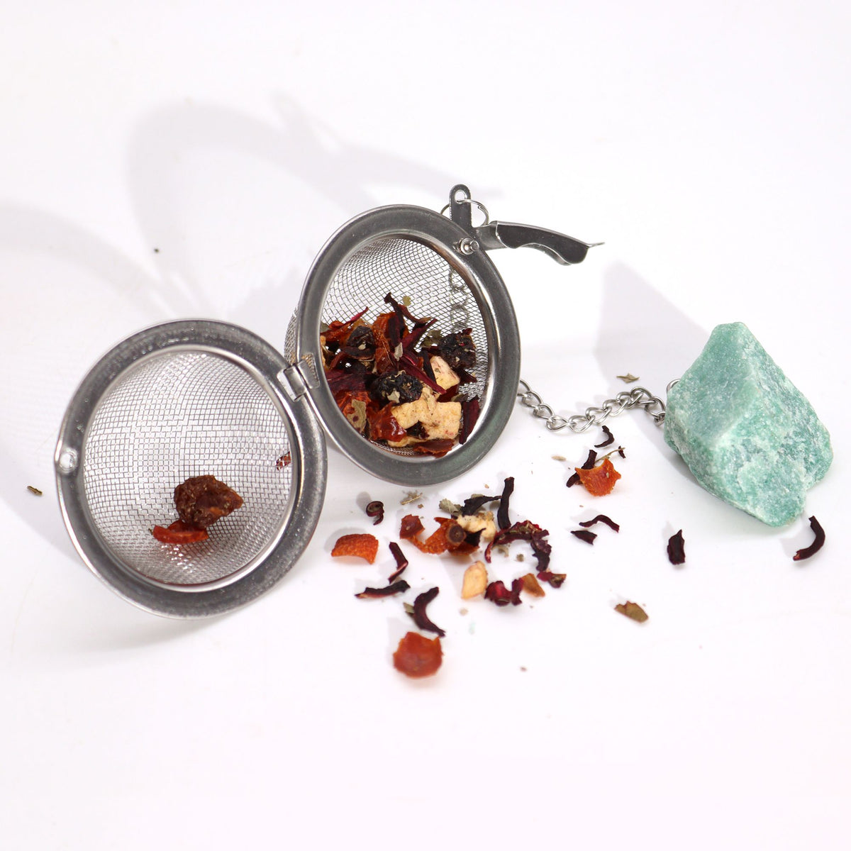 Tea infuser with loose tea leaves on a white background