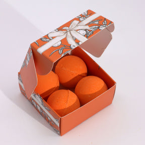 Orange bath bombs in a decorative box with floral design on a white background