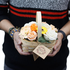 Person holding a basket of soap flowers with a decorative tag