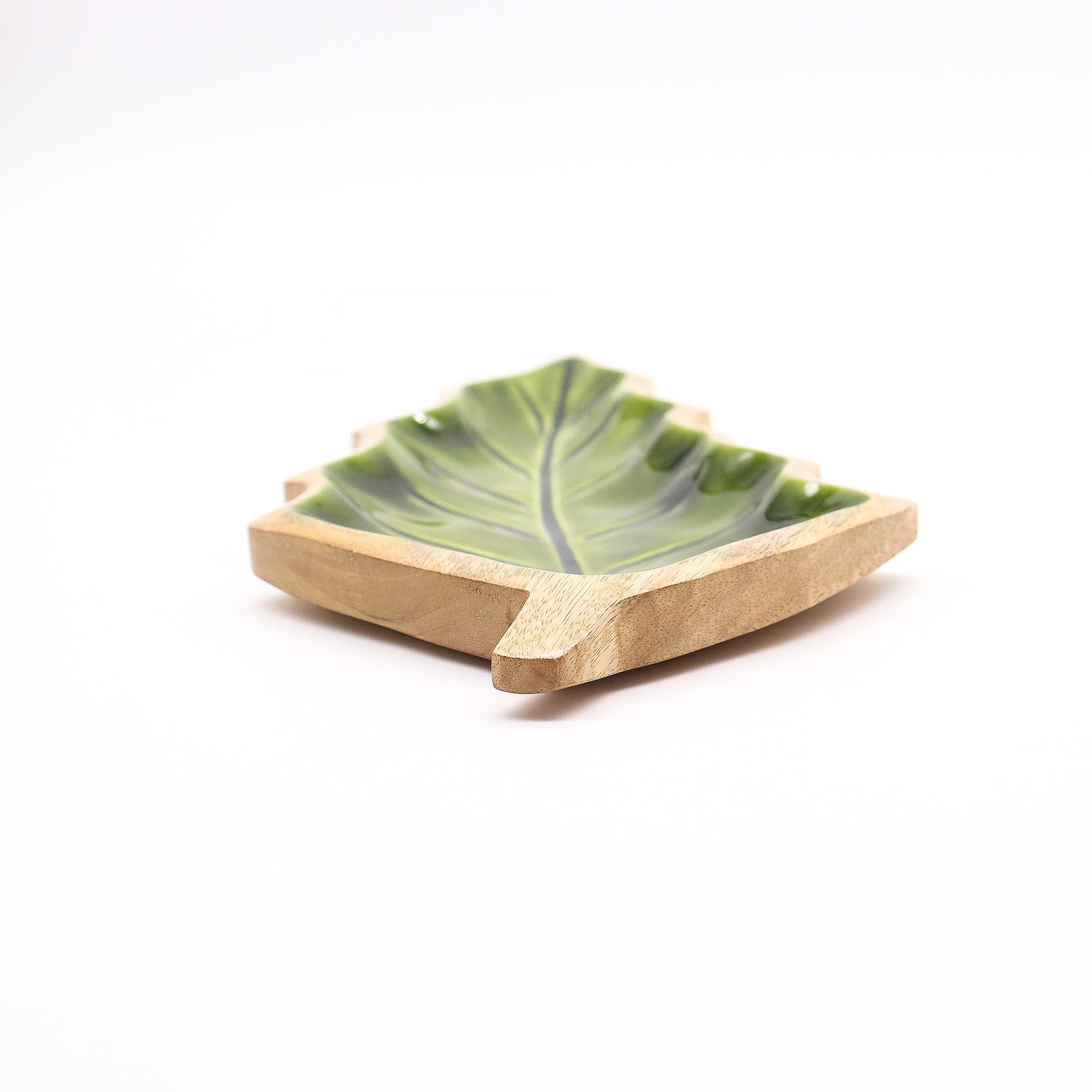 Large leaf-shaped mango wood bowl with rich green enamel inside, filled with pine cones and candles on autumn table setting