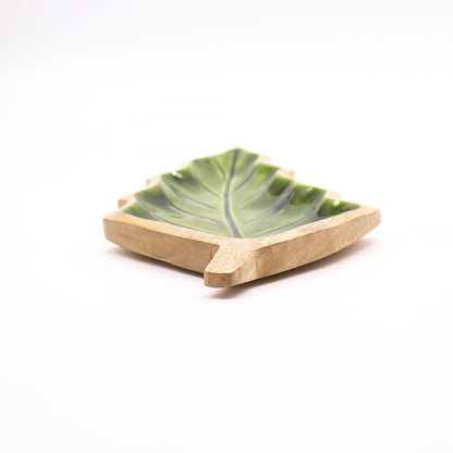 Large leaf-shaped mango wood bowl with rich green enamel inside, filled with pine cones and candles on autumn table setting