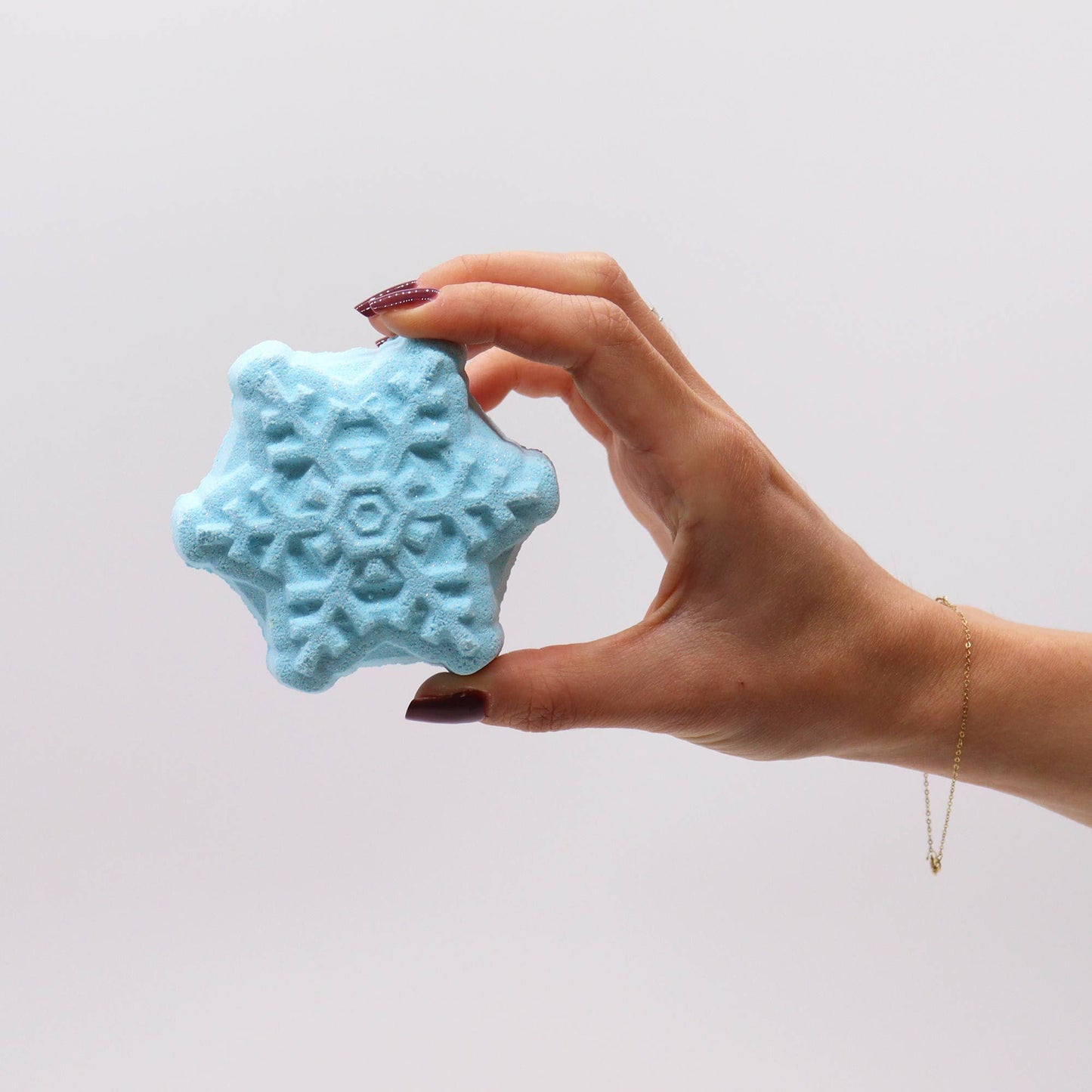 Hand holding a blue snowflake bath bomb