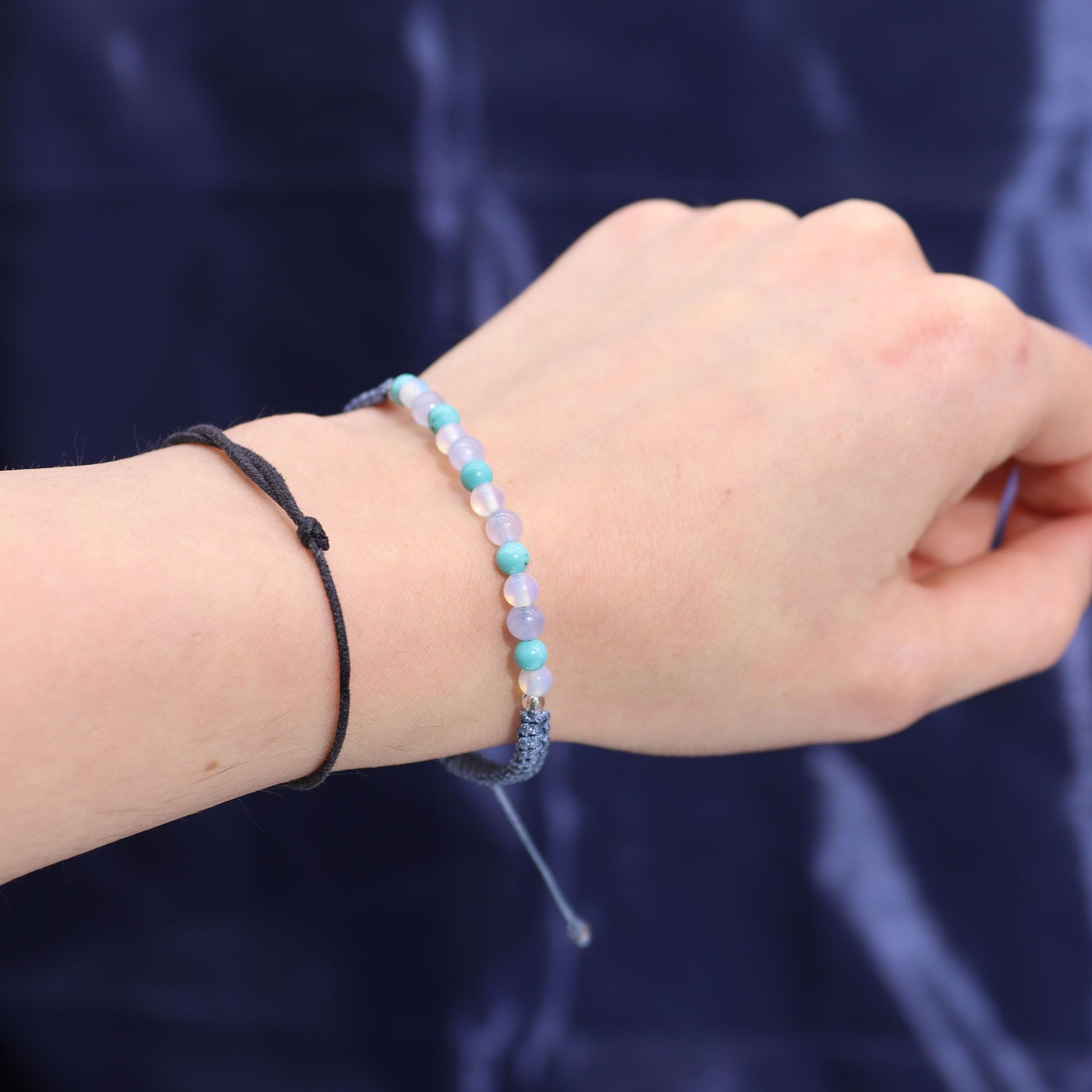 Close-up of a hand wearing two beaded bracelets