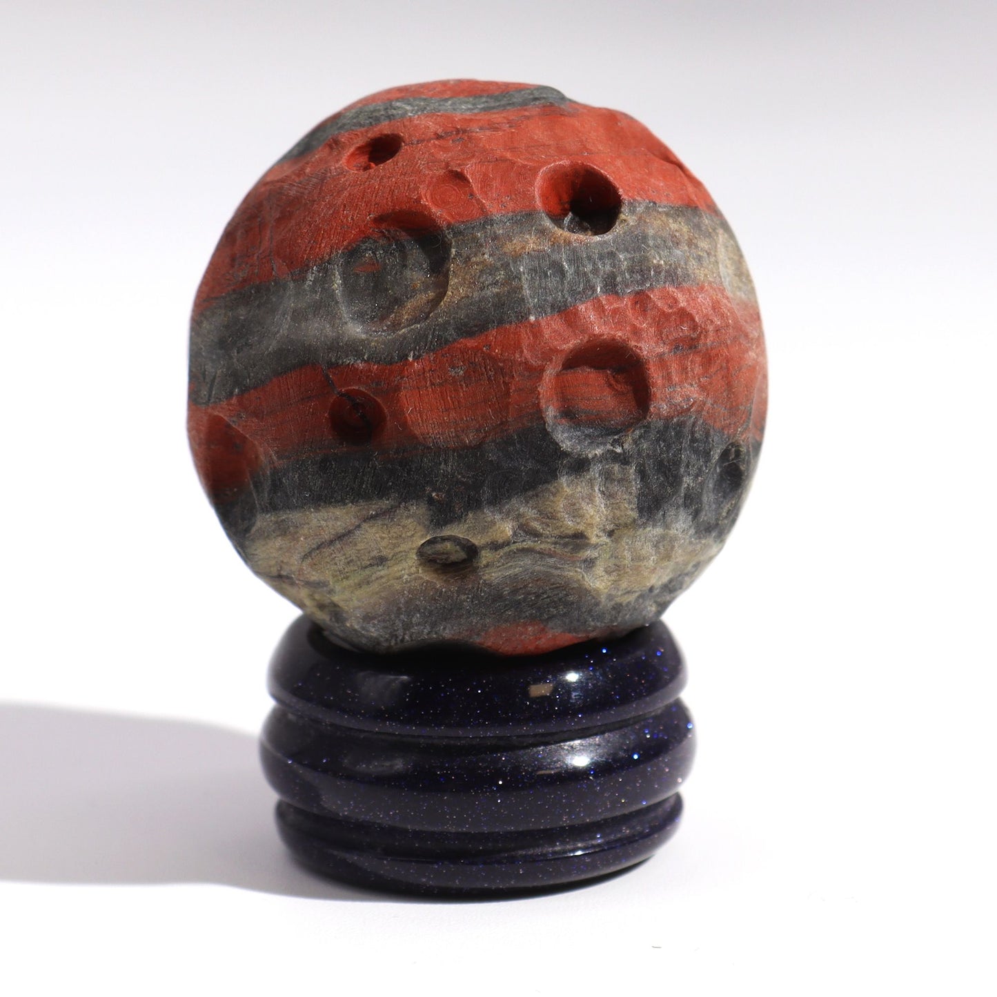 40mm deep red Jasper Mars sphere dramatically lit on sparkling goldstone ring stand against dark cosmic background with fiery glow