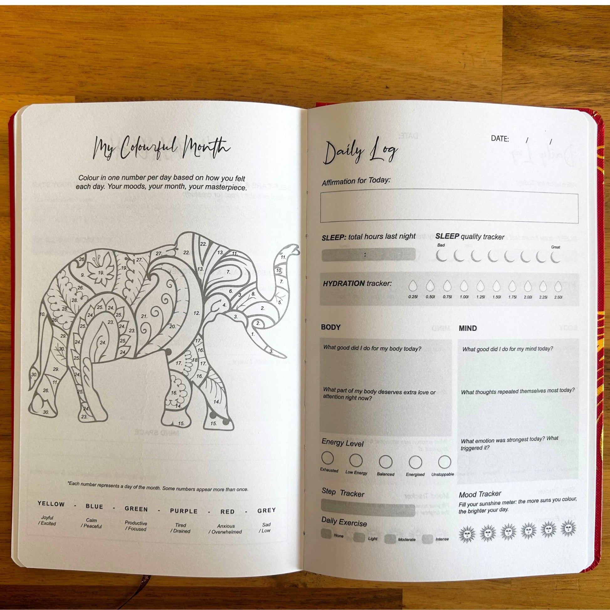 Open journal with coloring page of an elephant and daily log on a wooden surface