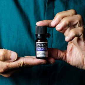 10ml amber glass bottle of pure Lavender Essential Oil with black dropper cap, fresh lavender sprigs