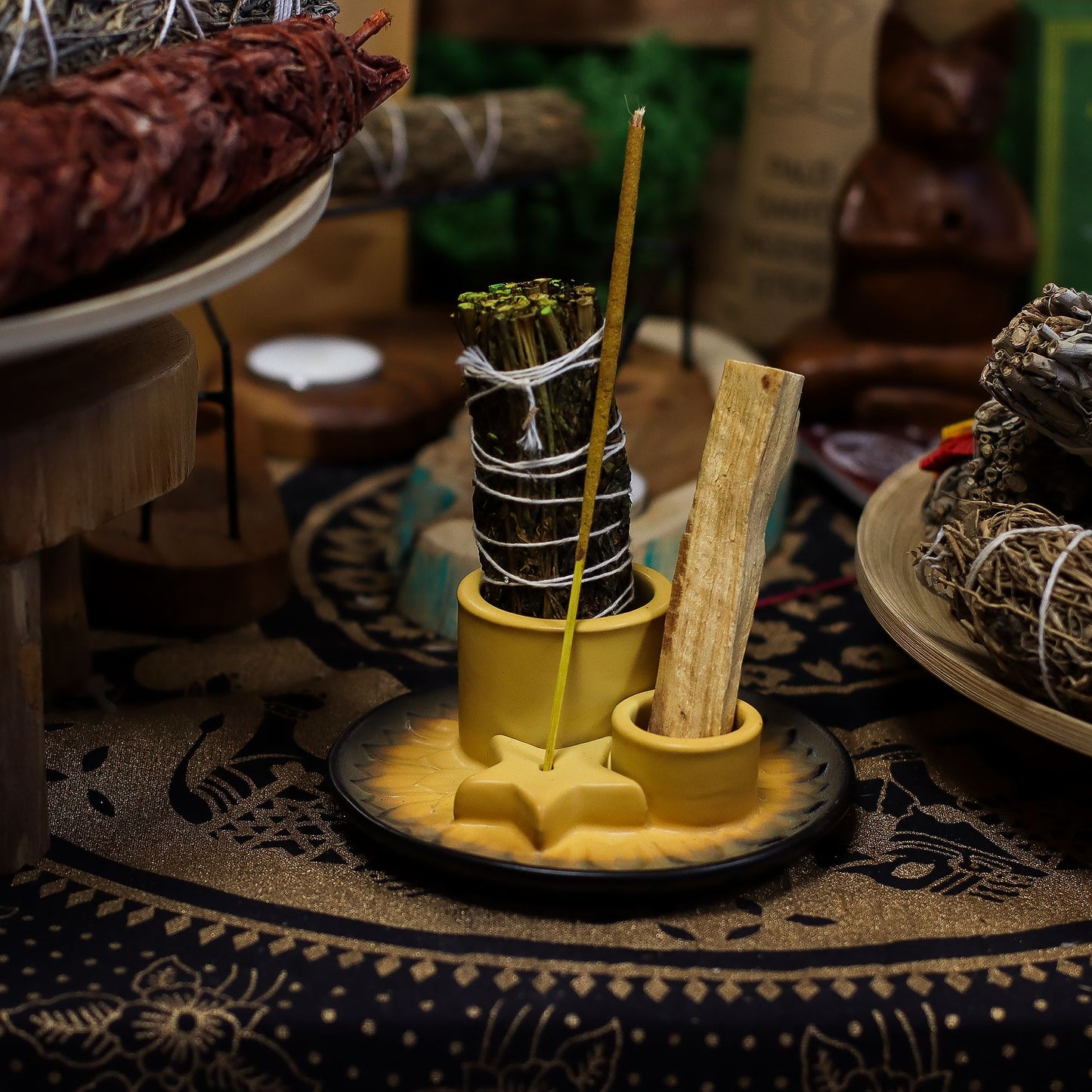 Speckled sand & grey ceramic mandala smudge holder with Palo Santo stick burning, sage bundle and incense cone, styled on neutral linen altar