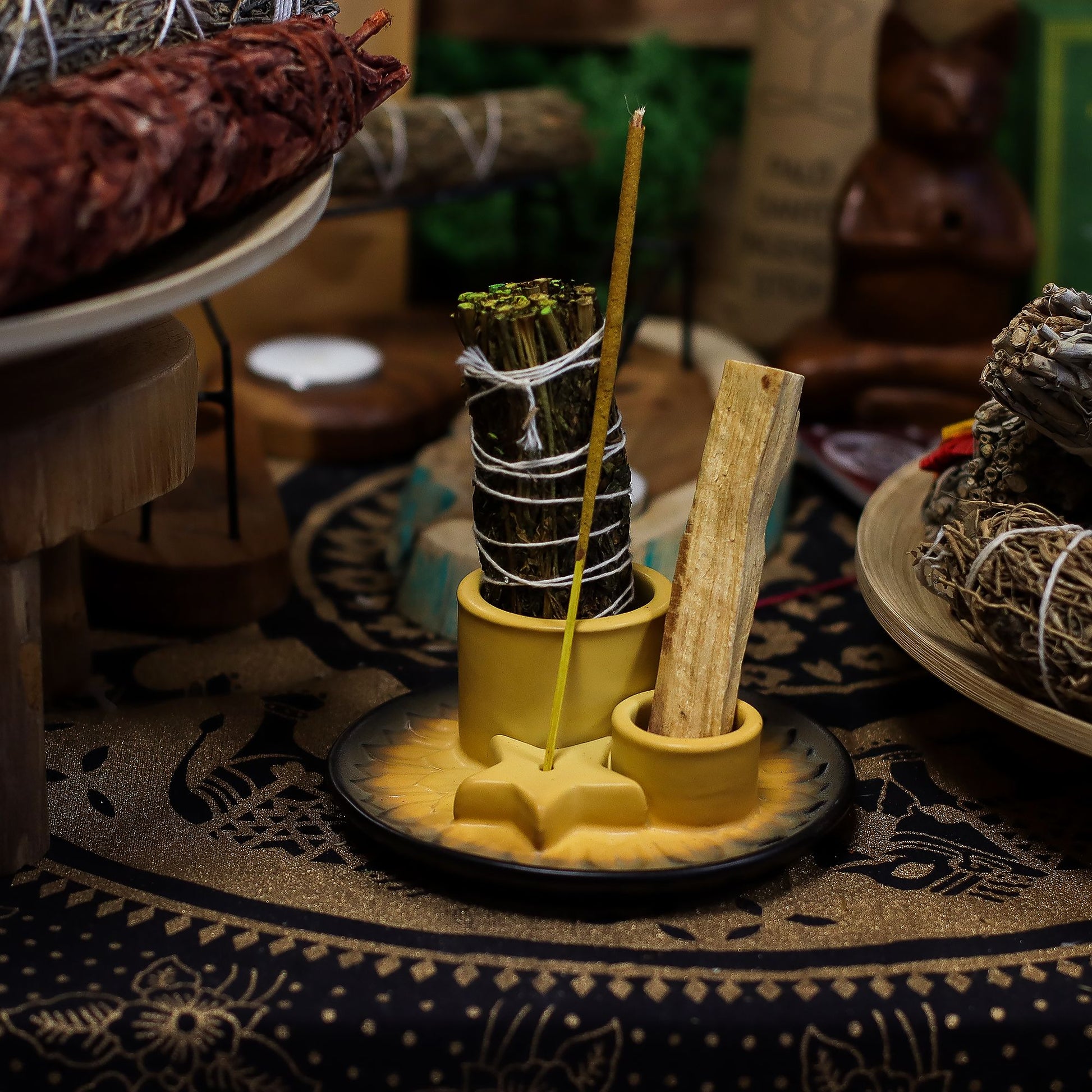 Speckled sand & grey ceramic mandala smudge holder with Palo Santo stick burning, sage bundle and incense cone, styled on neutral linen altar