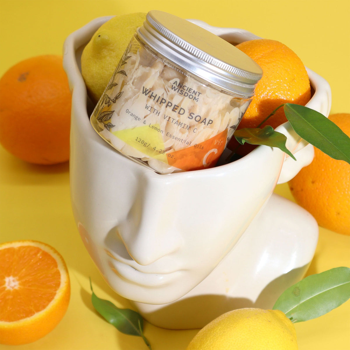 Jar of whipped soap with oranges and lemons on a yellow background