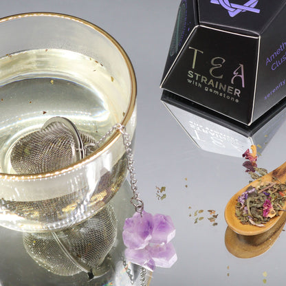 Tea strainer with gemstones next to a box labeled 'Tea Strainer with gemstones' on a reflective surface.