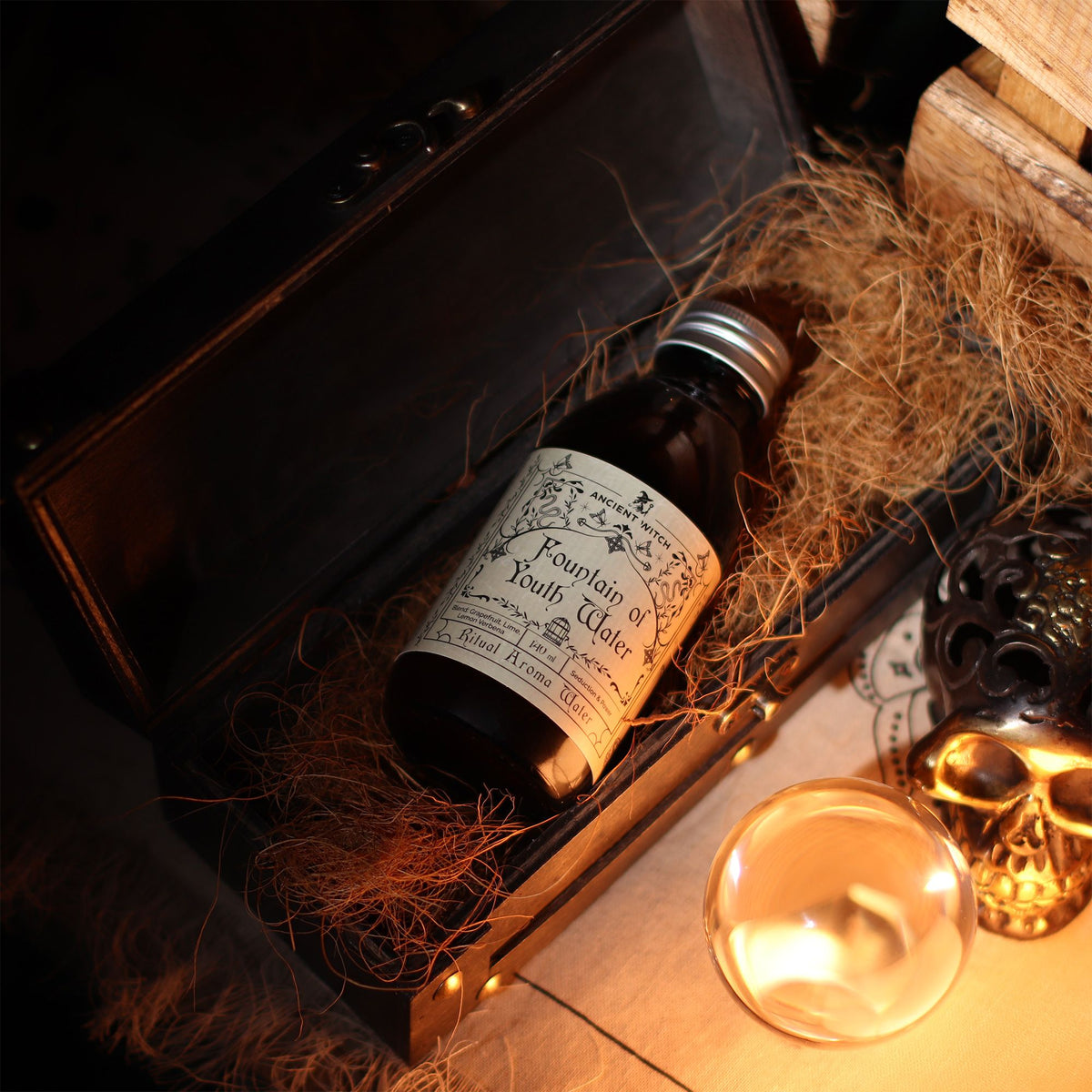 Bottle of 'Fountain of Youth Water' in a decorative box with hay, skull, and candle in the background.