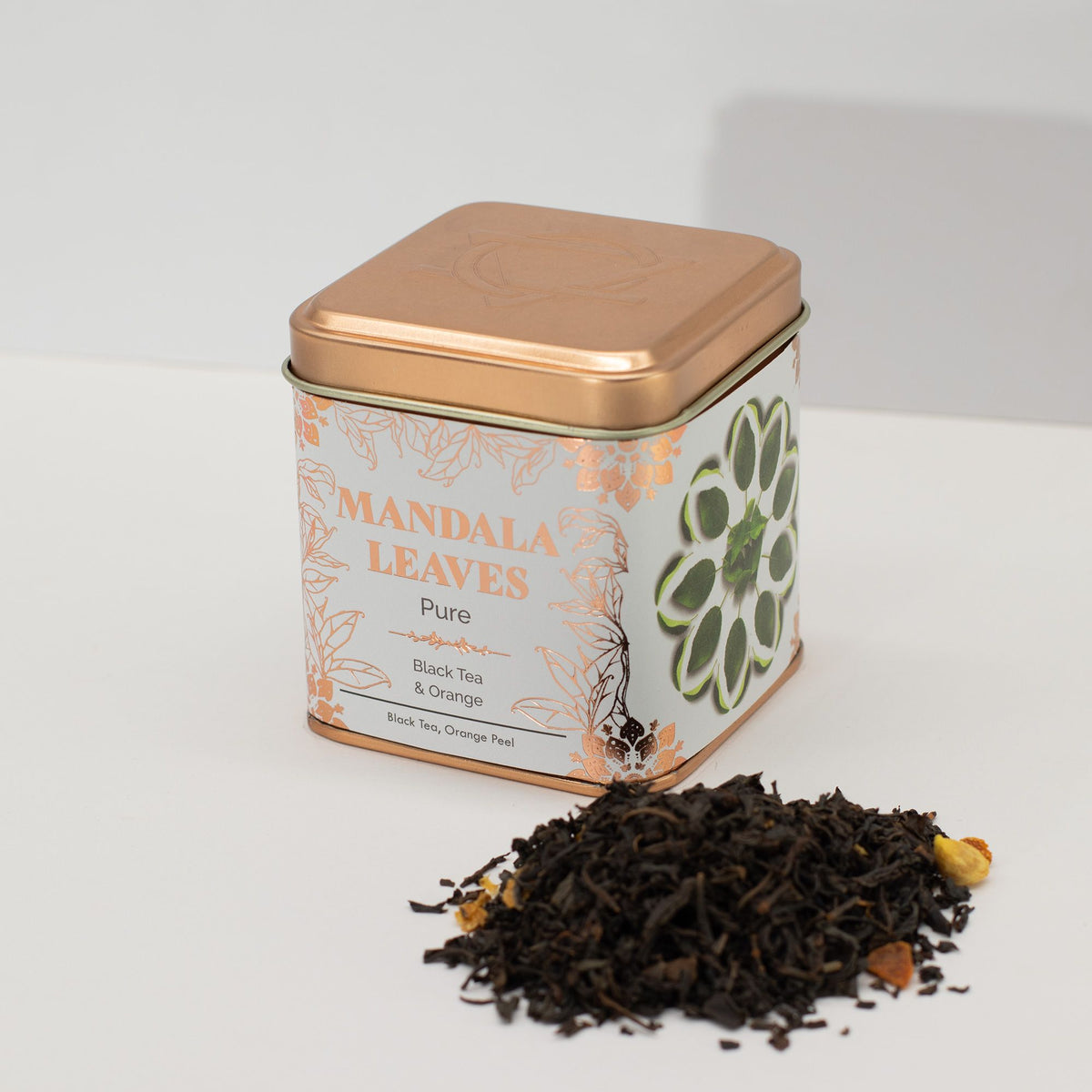 Tea tin labeled 'Mandala Leaves' with loose tea leaves on a white background
