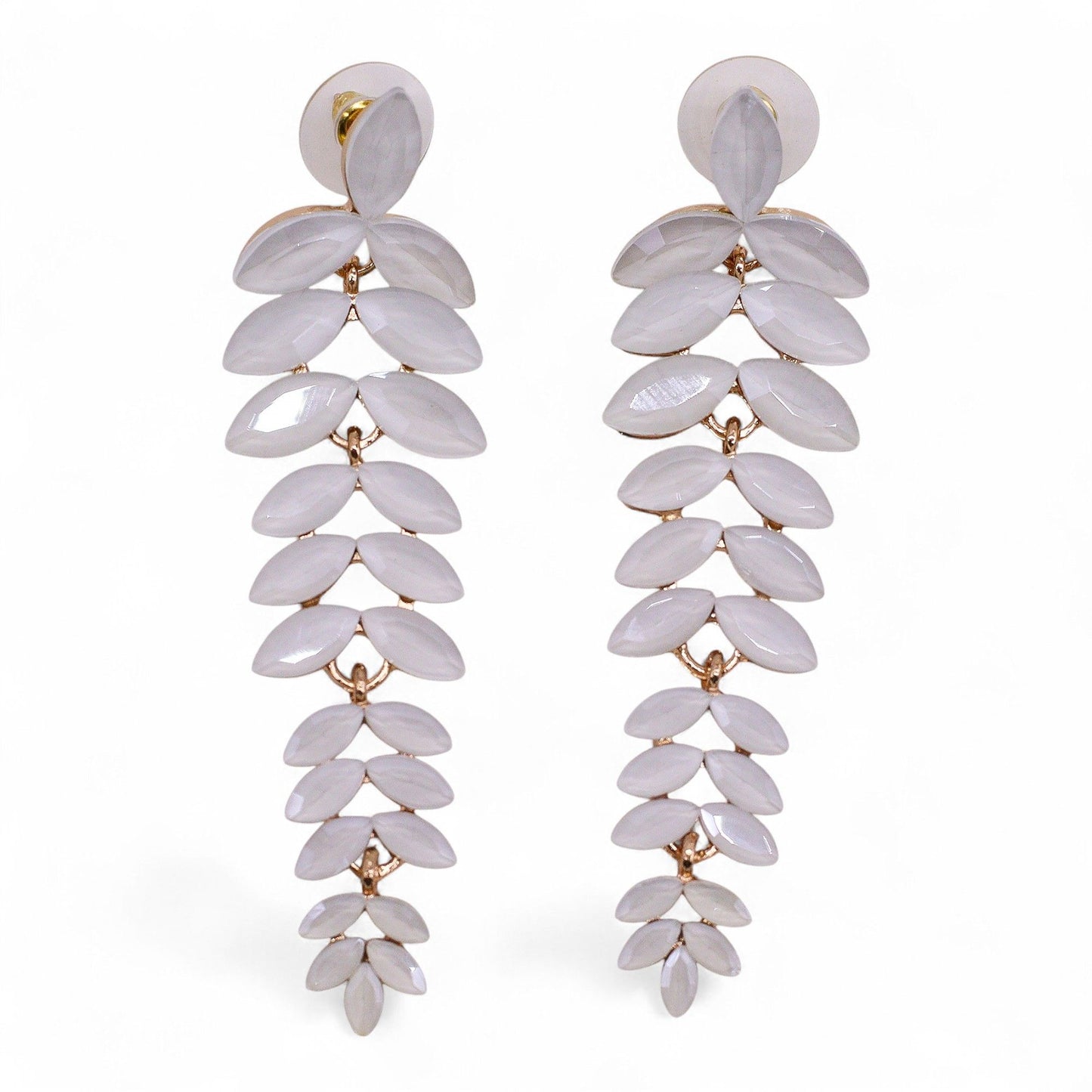 Delicate pearl-white vintage glass long drop earrings swaying gently, catching dawn light against soft white fabric and morning mist