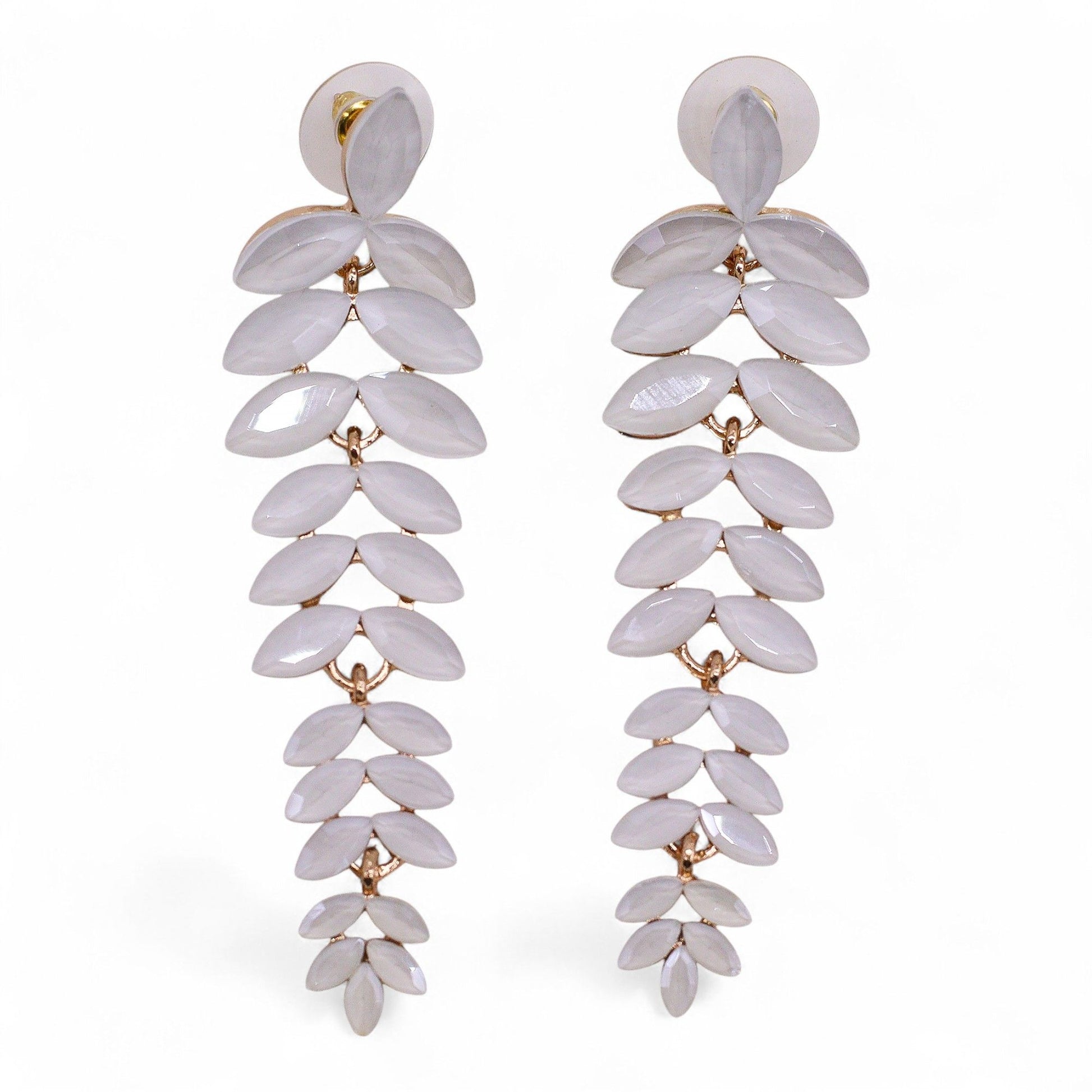 Delicate pearl-white vintage glass long drop earrings swaying gently, catching dawn light against soft white fabric and morning mist