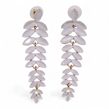 Delicate pearl-white vintage glass long drop earrings swaying gently, catching dawn light against soft white fabric and morning mist