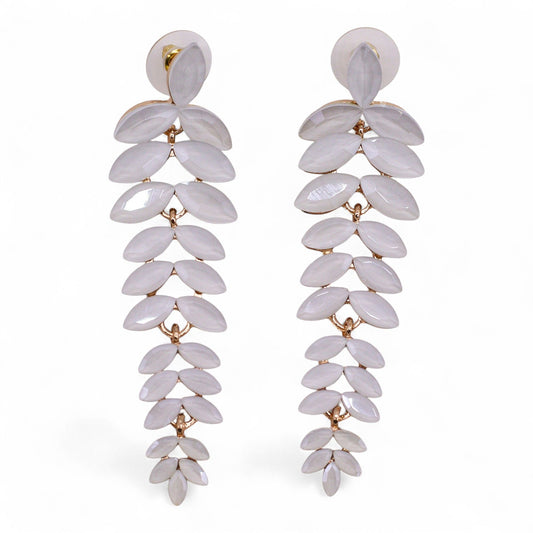 Delicate pearl-white vintage glass long drop earrings swaying gently, catching dawn light against soft white fabric and morning mist