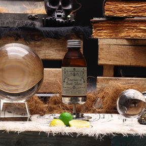 Close-up of ritual water bottle with dropper cap, golden liquid shimmering inside, citrus essential oils visible through glass