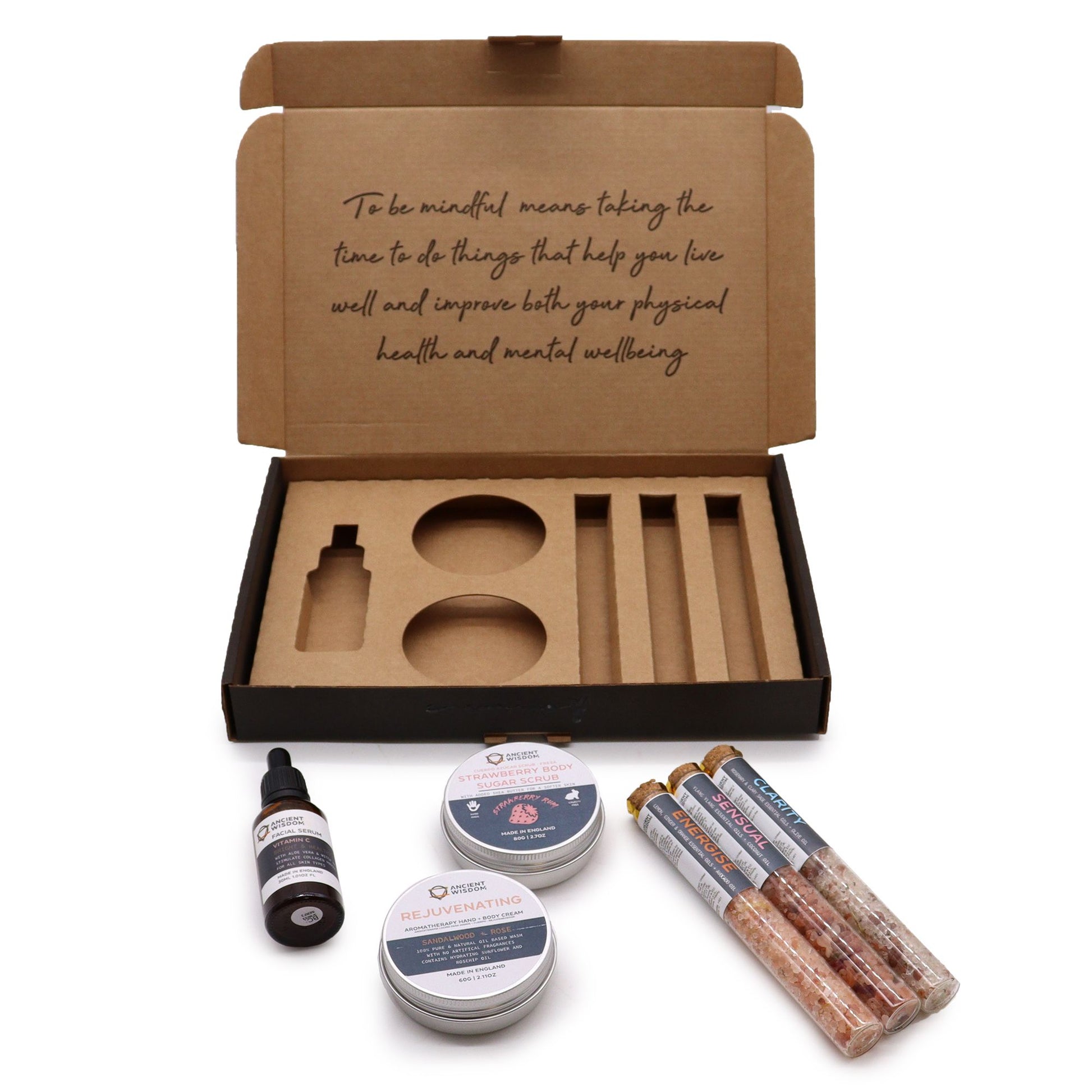 Serenity Essential Self Care Kit in elegant gift box open to reveal strawberry scrub jar, body cream, three bath salt vials, Vitamin C serum dropper bottle, fresh strawberries and lavender sprigs on marble