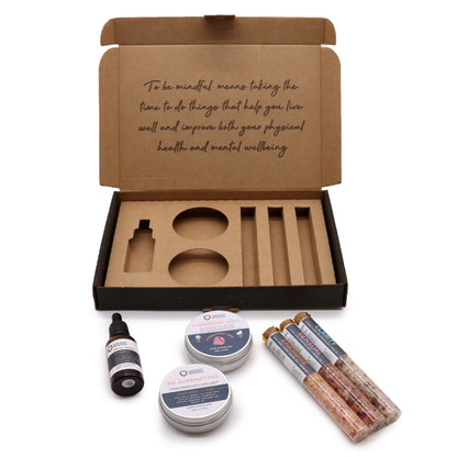 Serenity Essential Self Care Kit in elegant gift box open to reveal strawberry scrub jar, body cream, three bath salt vials, Vitamin C serum dropper bottle, fresh strawberries and lavender sprigs on marble