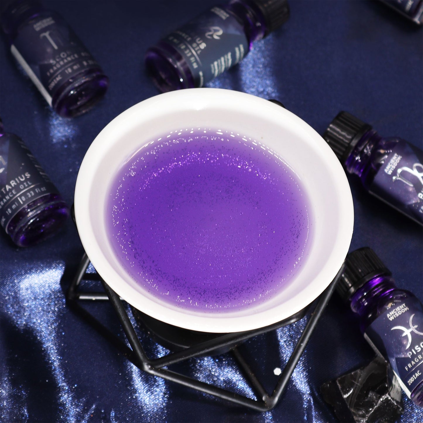 Purple liquid in a white bowl surrounded by dark bottles on a reflective surface