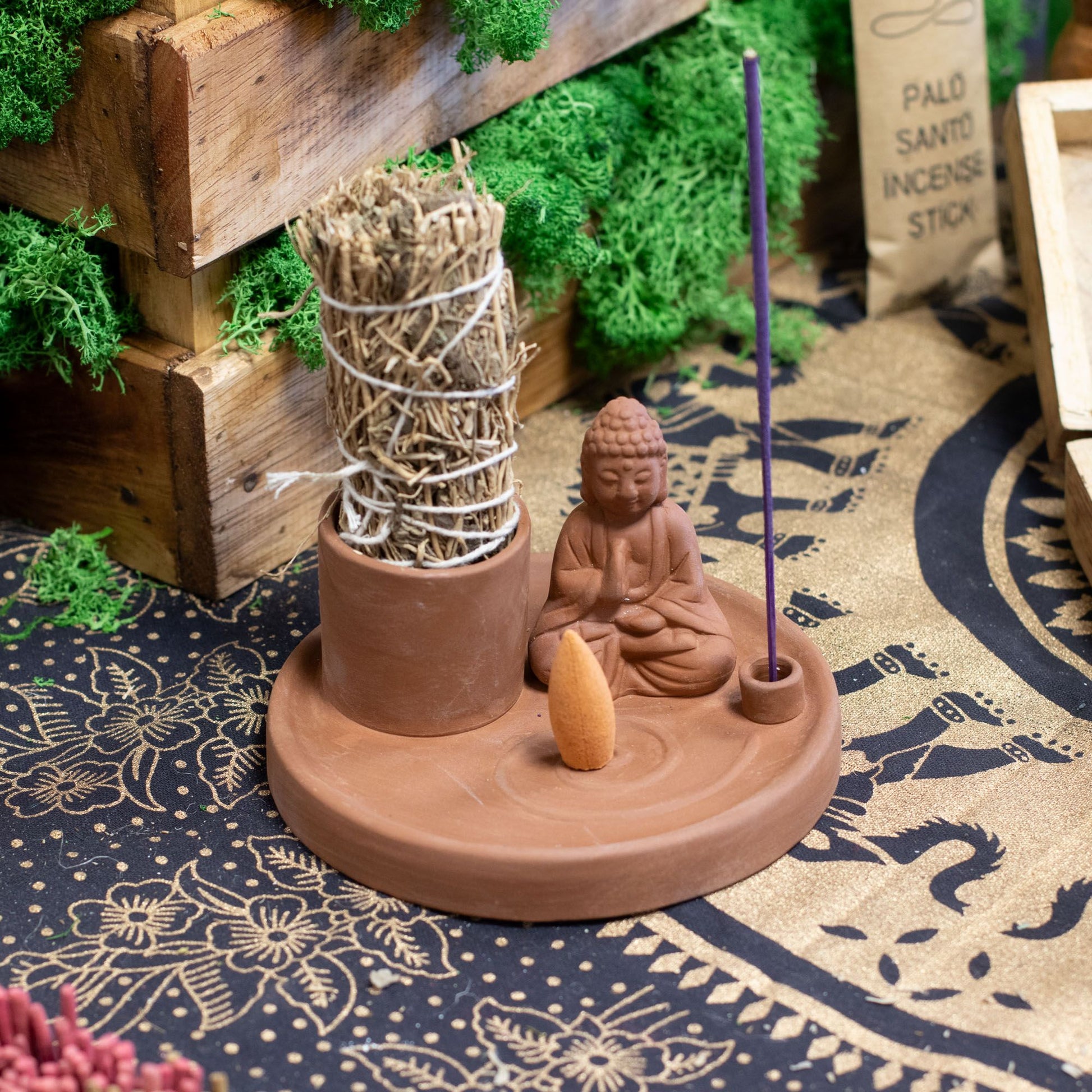 Incense burner with Buddha figure and incense sticks on a decorative rug
