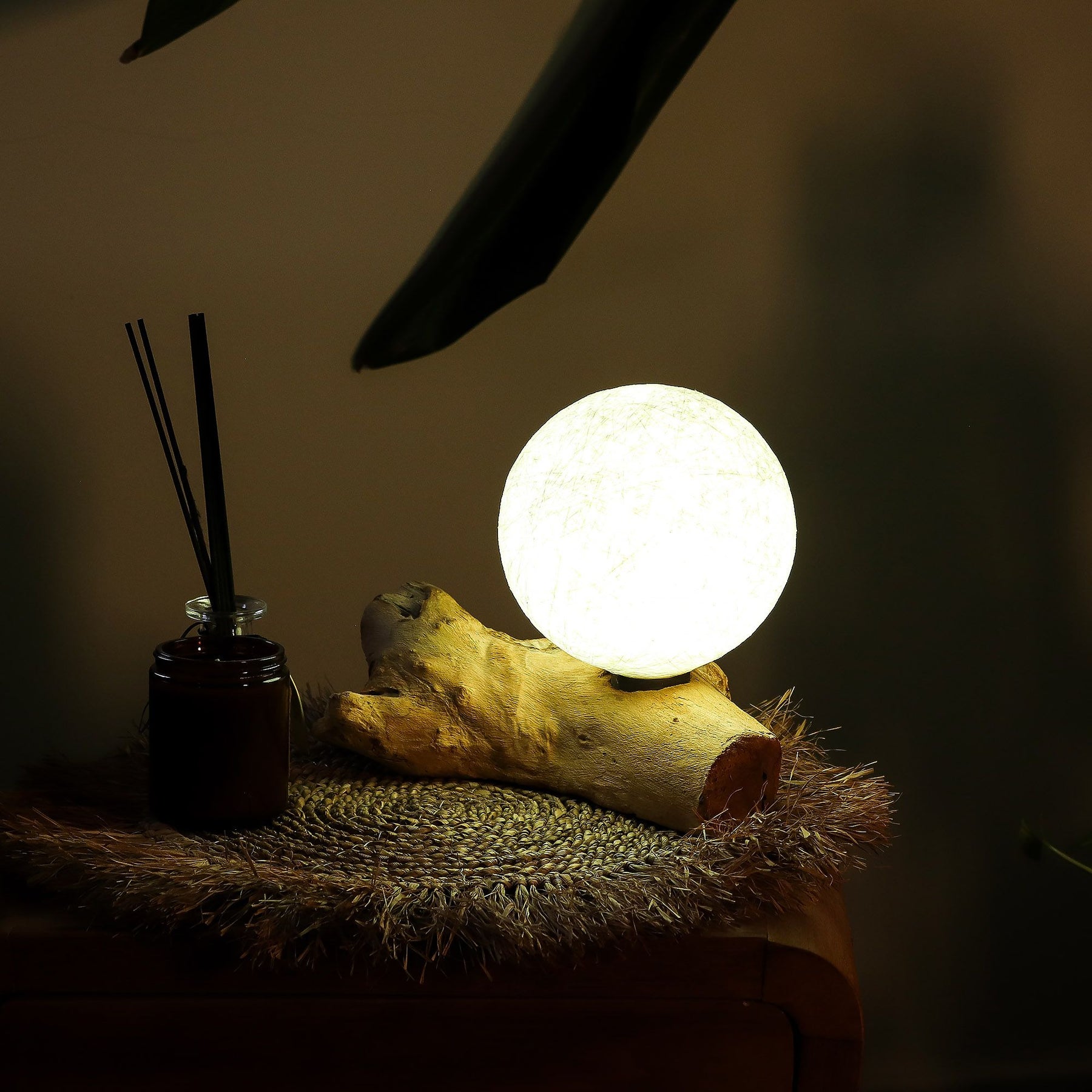 Glowing spherical lamp on a wooden log with diffused light in a dimly lit room.