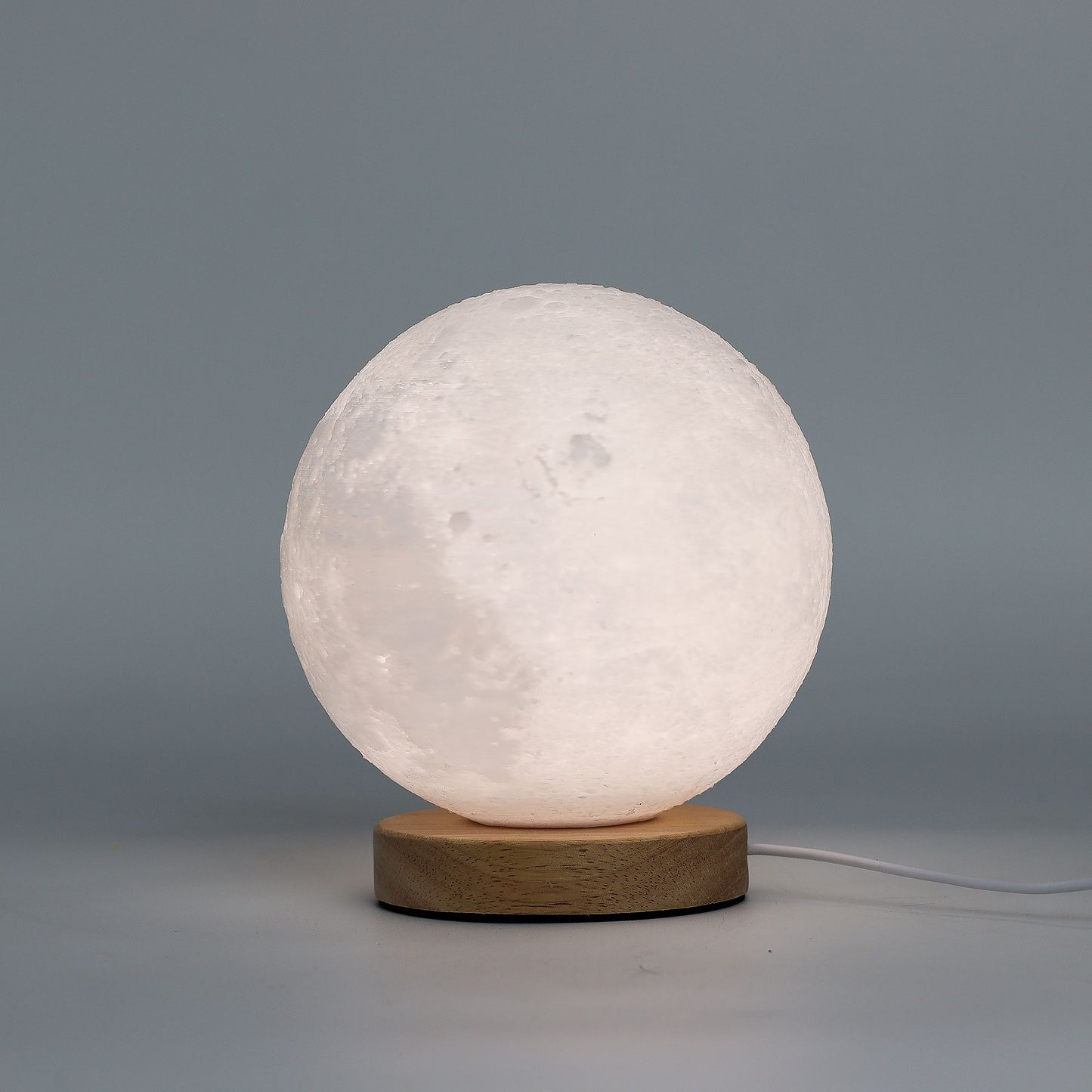 Moon New Wave USB lamp with textured honeycomb surface and crescent moon-inspired shape, warm glow on 3rd brightness setting, placed on wooden base